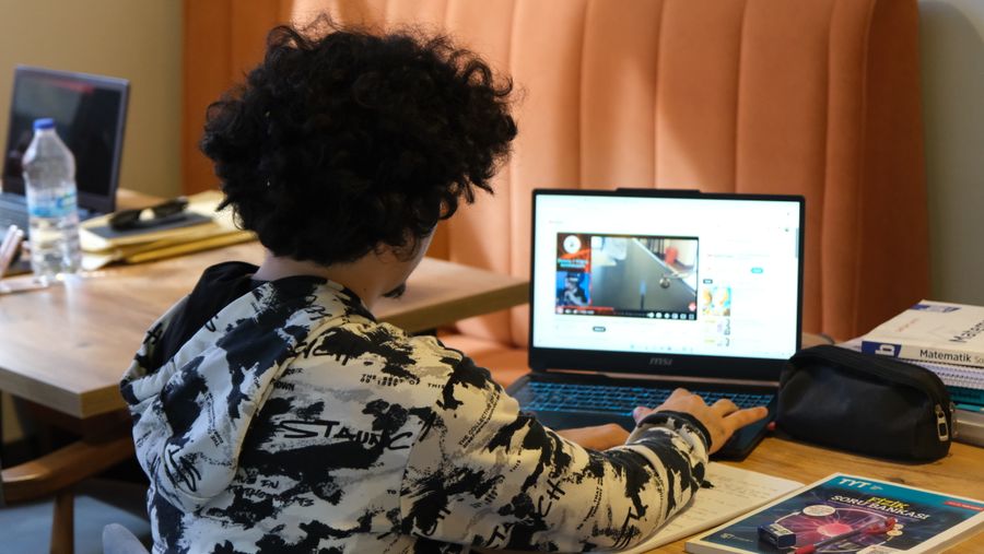 Person preparing notes beside a laptop